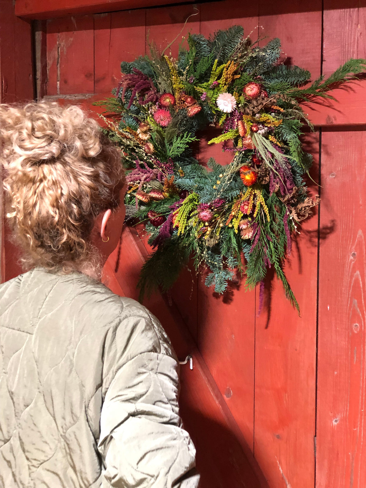 Dame beundrer høstkransen hun har laget selv på kurs hos Marka Blomster
