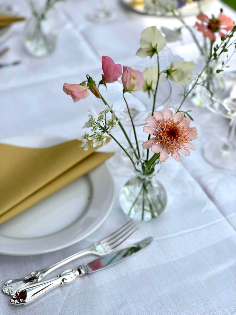 Bord dekket  til fest med liten vase med åkerblomster fra Marka Blomster ved hver tallerken